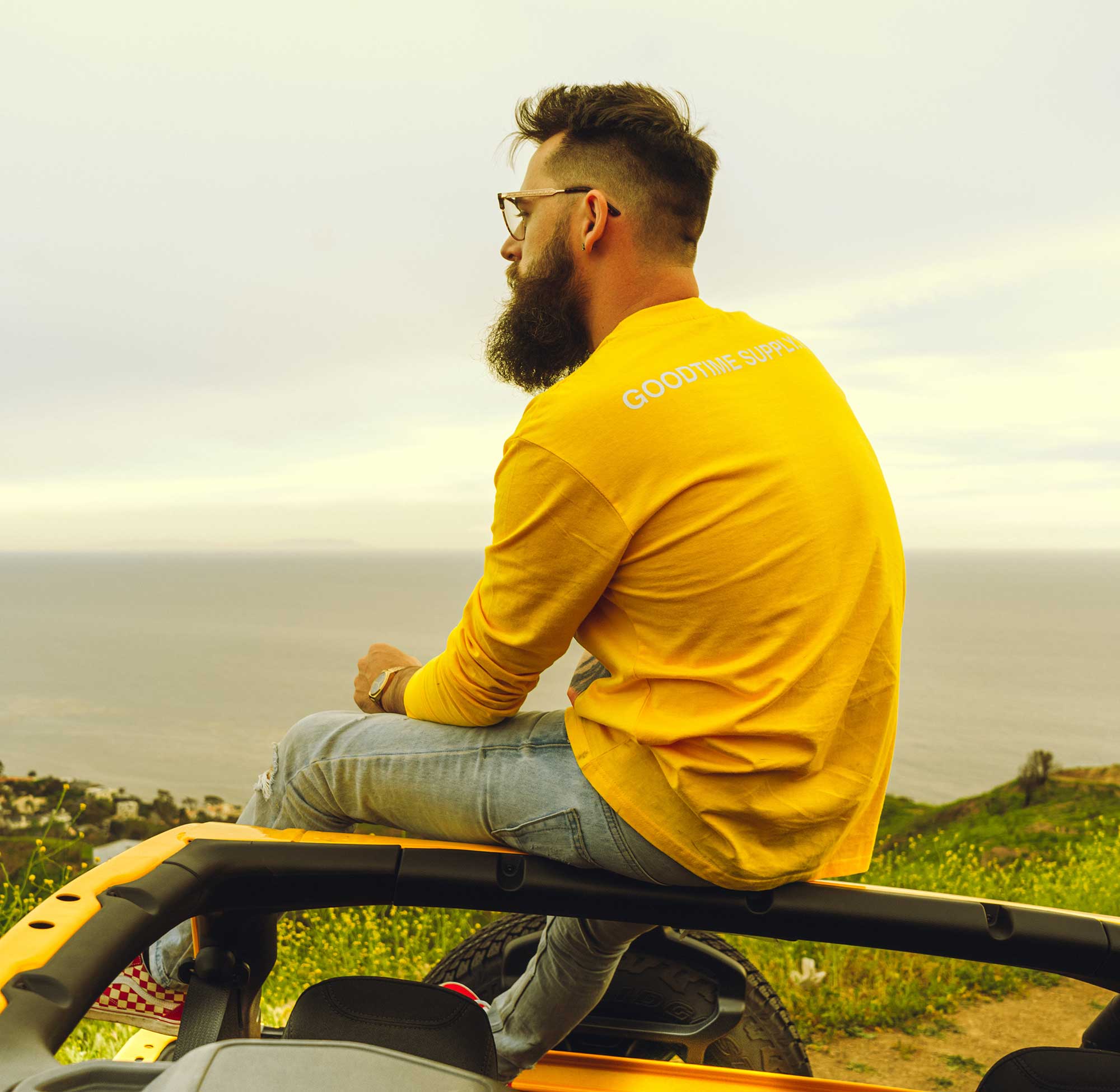 A Man With Glasses Sitting on a Vehicle Looking at the Horizon.