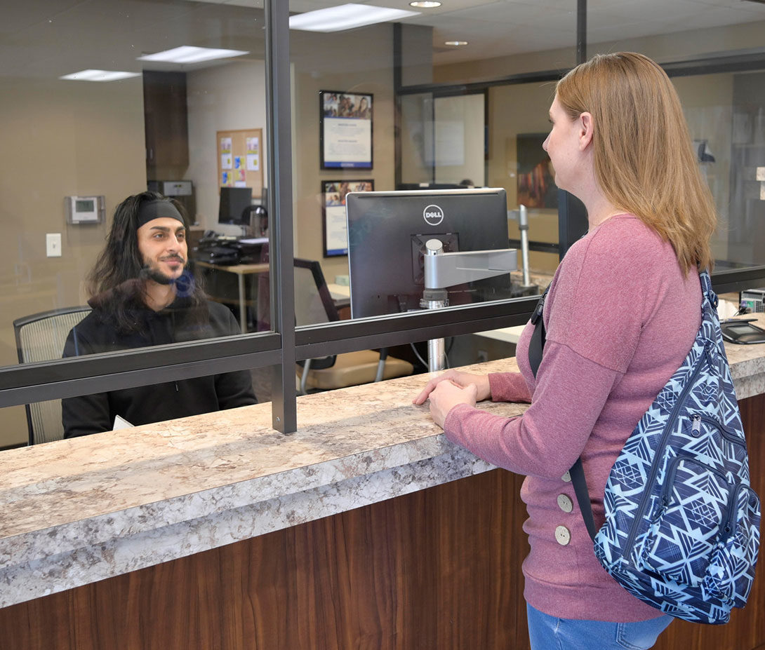 A Woman Standing at a Counter Talking to a Team Member for a CODAC Same-day Intake.