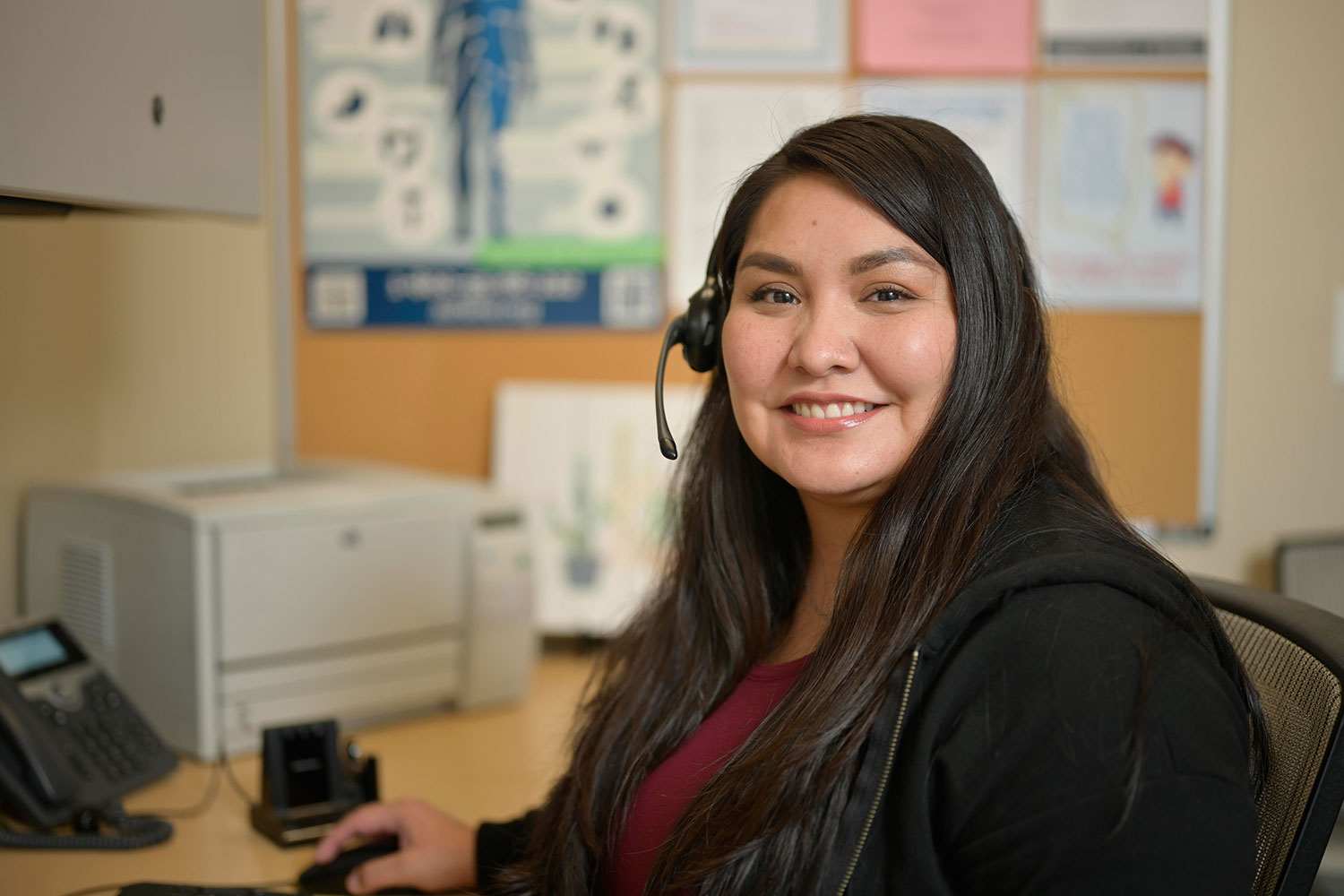 CODAC Treatment Team Member Sitting at a Desk With a Headset Smiling.