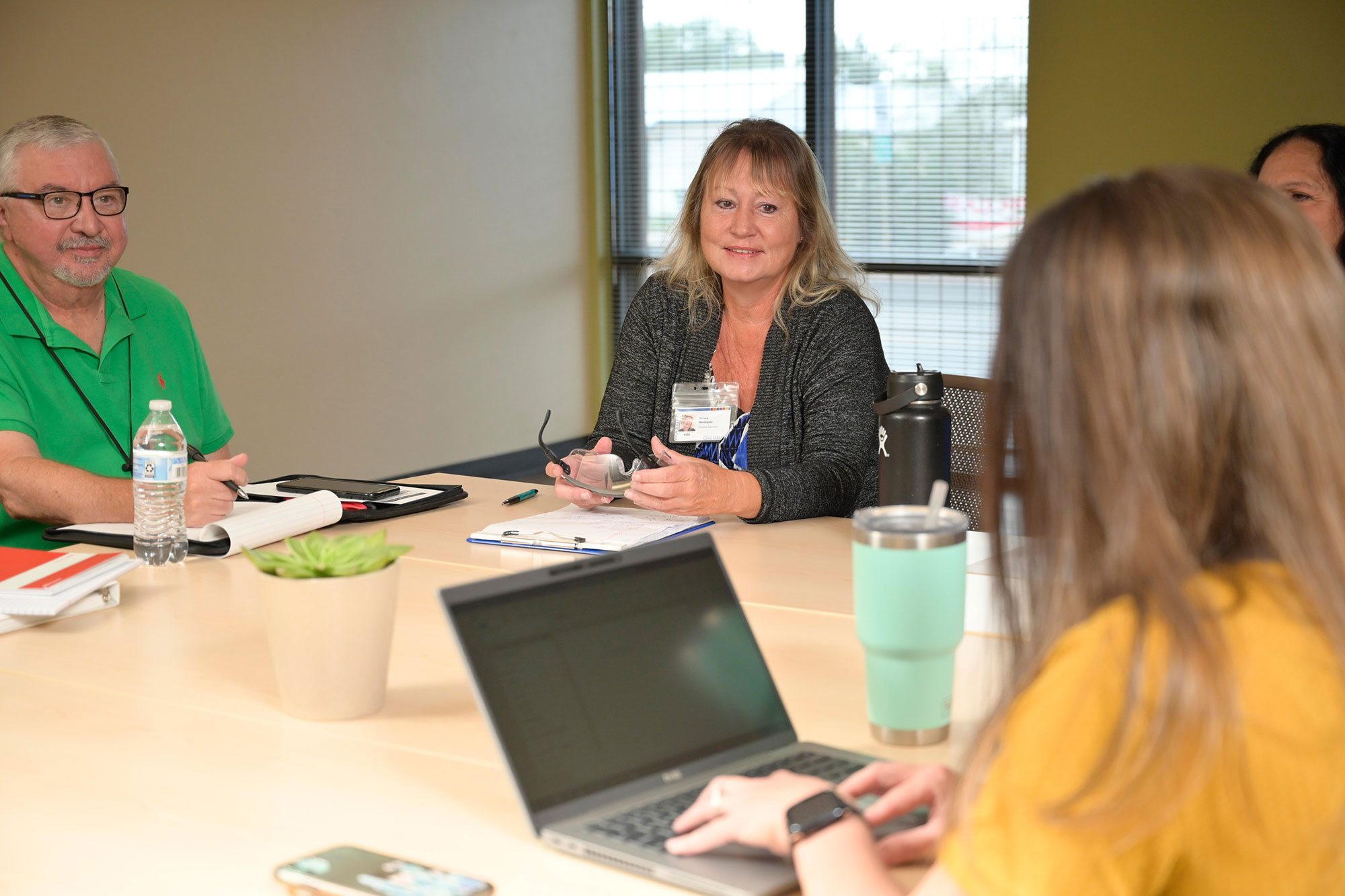 A Group of People Sitting Around a Table With a Laptop for CODAC Counseling and Therapy Services.