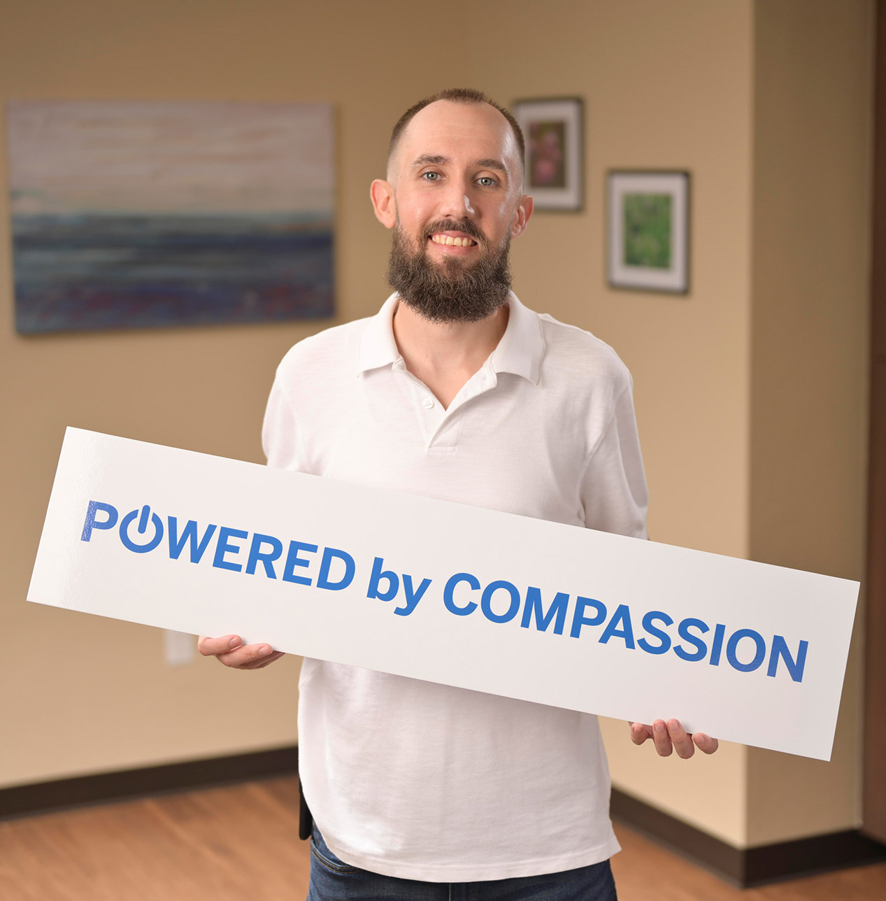 A Person Holding a Powered by Compassion Sign at CODAC.