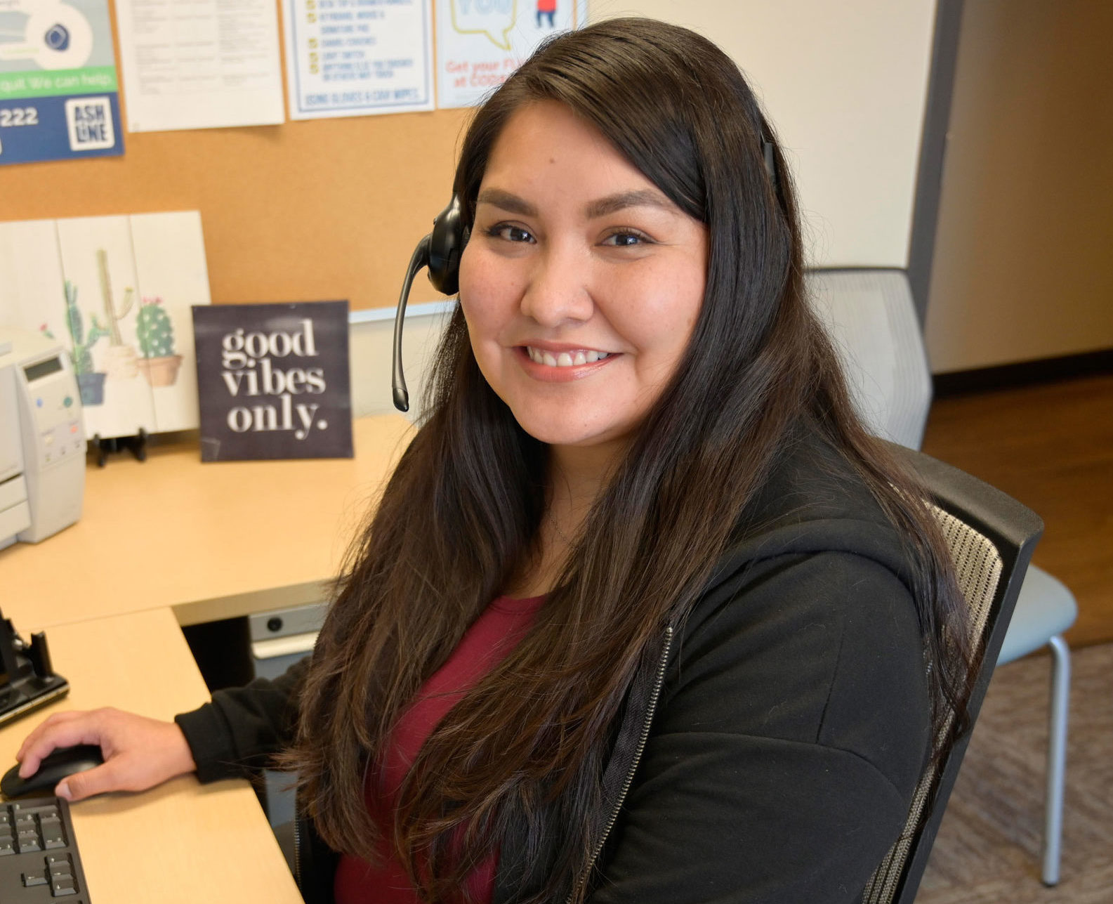 A CODAC Team Member Sitting at a Desk With a Headset Smiling.
