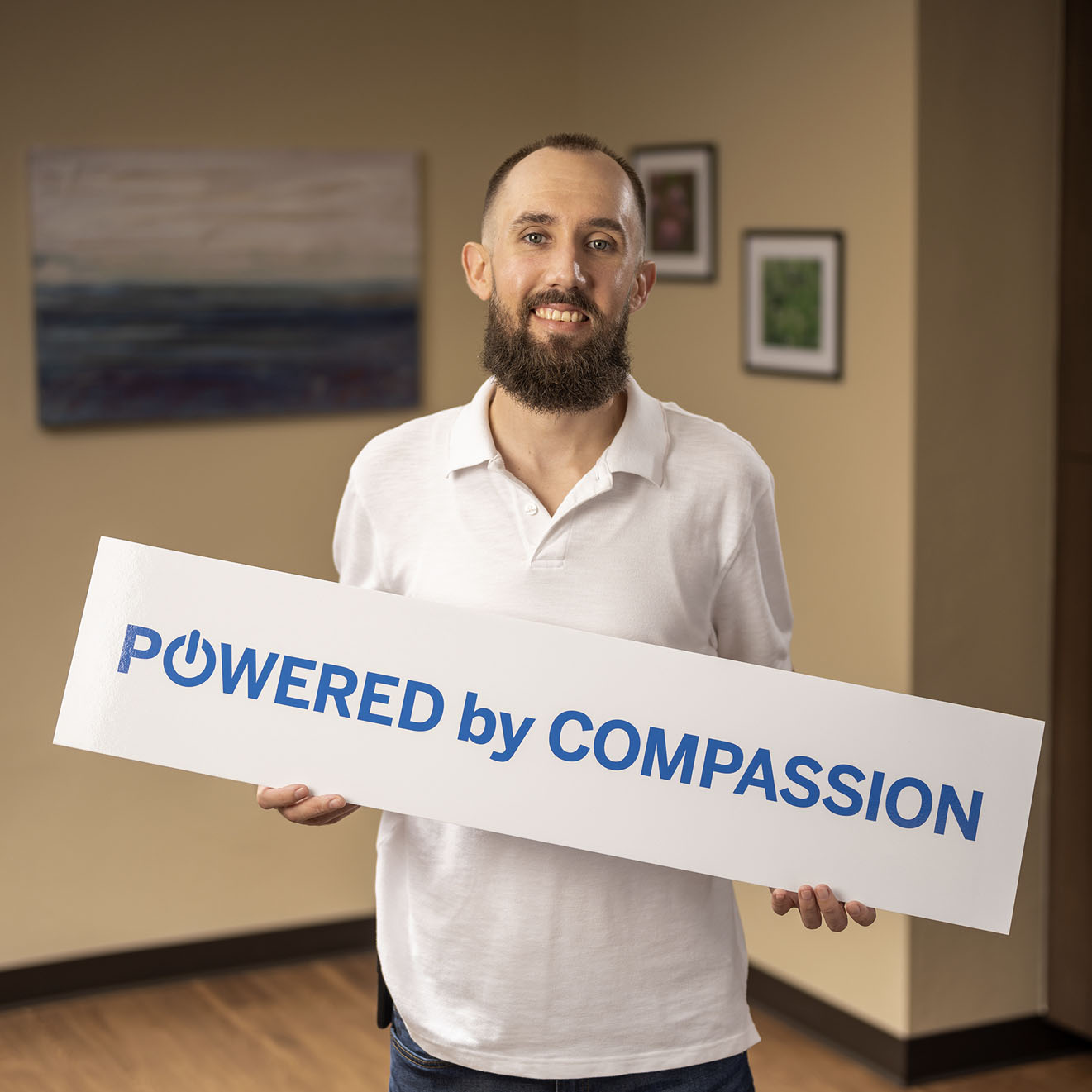 CODAC peer support specialist holding Powered by Compassion Sign.